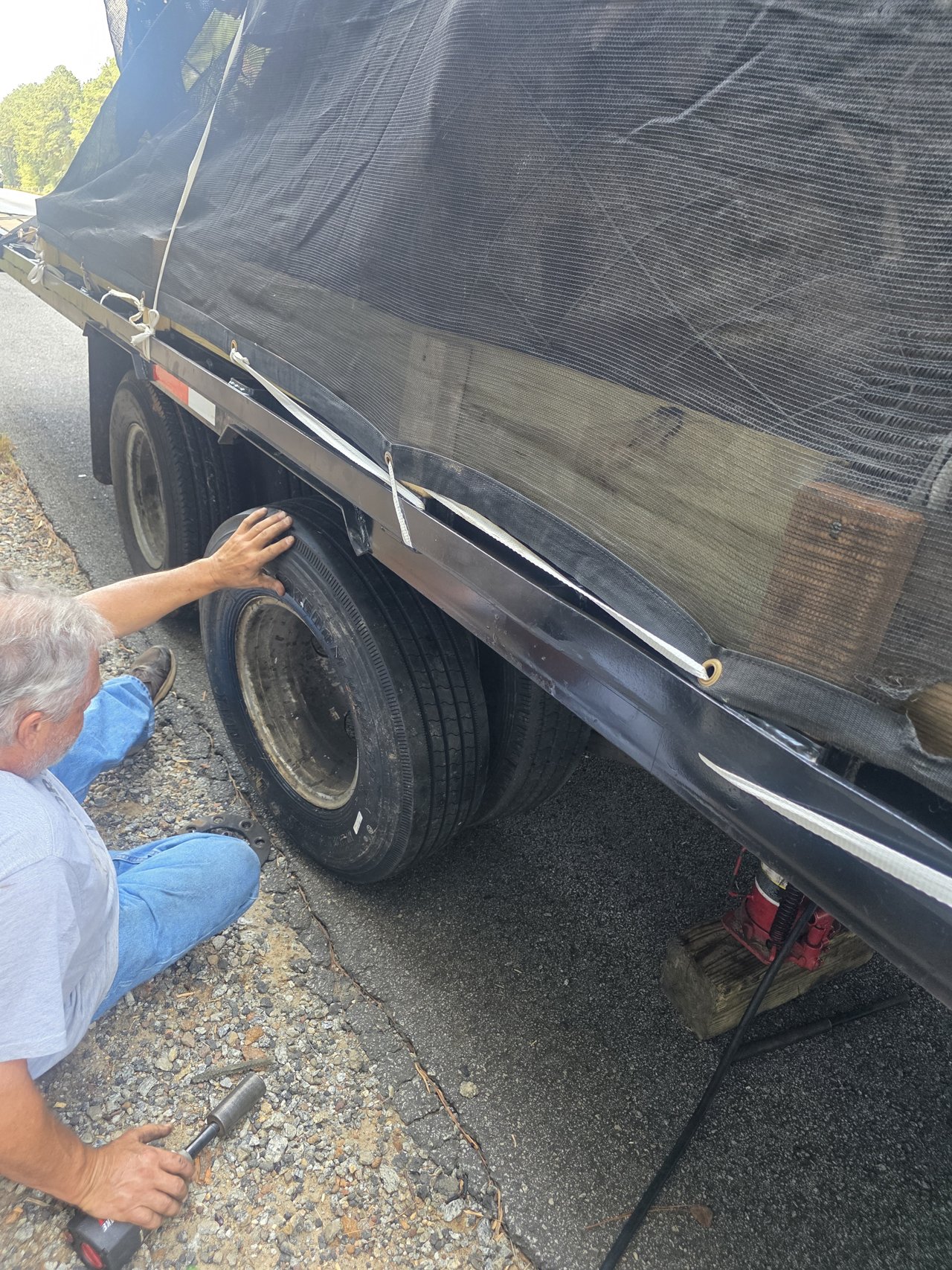 Technician working on a gooseneck trailer tire roadside in Crawfordville, Georgia.